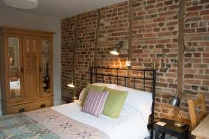 a bedroom with a bed with a brick wall at The Crown Aldbourne in Aldbourne