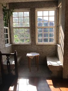 a room with two windows and a bench and a table at Camelia Rooms in Guimarães