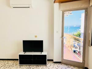 ein Wohnzimmer mit einem TV und einer Tür zu einem Balkon in der Unterkunft LLOTJA - Apartamento en la playa y el centro de Roses in Roses