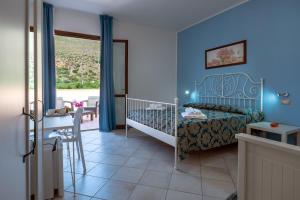 a bedroom with a bed and a table and a window at Hotel Achibea in San Vito lo Capo