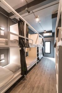 a dorm room with bunk beds and a wooden floor at The Cocoon Hostel in Bangkok
