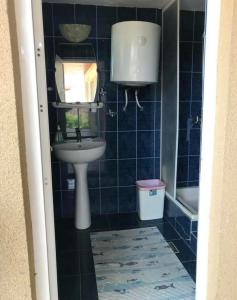 a blue tiled bathroom with a sink and a tub at Casa Lenuta in Mila Douăzeci şi Trei