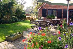 eine Terrasse mit einem Tisch, Stühlen und Blumen in der Unterkunft Zum alten Krug in Wangerland