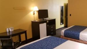 ein Hotelzimmer mit 2 Betten, einem Schreibtisch und einem TV in der Unterkunft Alexander House Motel in Park River