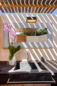 La salle de bains est pourvue d'un lavabo, d'un miroir et d'un vase fleuri. dans l'établissement Can Corda Formentera, à Cala Saona