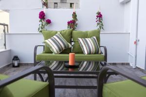a green couch with pillows and an orange candle on a table at Blue4Aqua Apartments in Kavála