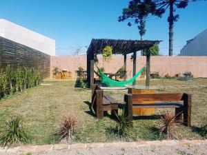 a park with benches and a hammock in the grass at Hotel Contorno Sul in Curitiba