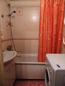 チェレポヴェツにあるКомфортабельный Люкс в Центреのバスルーム(オレンジ色のシャワーカーテン、洗濯機付)