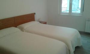 two white beds in a room with a window at Comercio 23 6º in Ribadesella