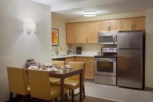 a kitchen with a table with chairs and a refrigerator at Cambridge Suites Mississauga in Mississauga