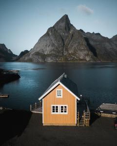 a house in the middle of a lake with a mountain at Olstind in Sakrisøy in Reine