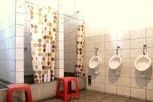 a bathroom with three urinals and two red stools at 1900 Backpacker's Hostel in Lima +82 photos