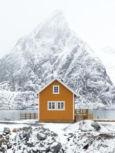 a small house in front of a snow covered mountain at Olstind in Sakrisøy in Reine