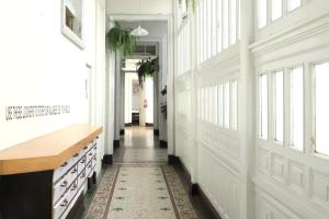 a hallway with white walls and windows and a rug at 1900 Hostel in Lima