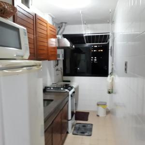 una pequeña cocina con fregadero y microondas en BARRA BELLA PRAIA RESIDENCE - Internet 350mb -TV -AR - Vista mar - Piscina climatizada- HomeOficce, en Río de Janeiro