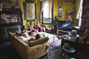 a group of people sitting in a living room playing video games at India House Hostel in New Orleans