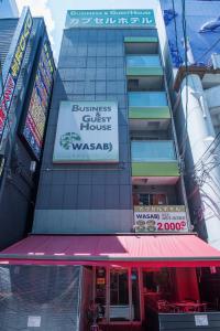 un edificio con un cartel para un establecimiento de negocios en HOSTEL WASABI Nagoya Ekimae, en Nagoya