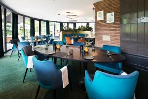 a dining room with tables and blue chairs at Auberge Du Bonheur in Tilburg