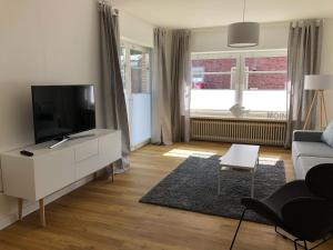 een woonkamer met een televisie en een bank bij Strandhütte in Norddeich