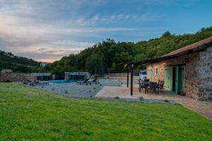 a stone building with a patio and a pool at Villa Natura in Vrbnik