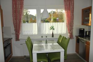 een keuken met een tafel en groene stoelen en een raam bij Ferienwohnung Dellori in Winterberg