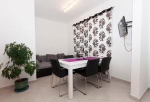 une salle à manger avec une table blanche et des chaises noires dans l'établissement Apartmani Olives, à Nin