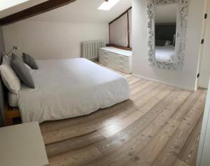 um quarto com uma cama branca e um espelho em Appartamento i Sentieri 23 em Riva del Garda