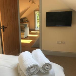 a bedroom with towels on a bed with a flat screen tv at The Old Winery Loft in Edale