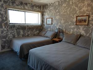 two beds in a room with a window and wallpaper at Swiss Mountain Motel in Thayne