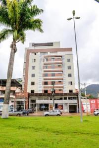 um grande edifício com uma palmeira num parque em Grand Café Hotel em Manhuaçu
