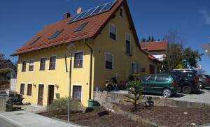 uma casa amarela com um telhado com painéis solares em Ferienwohnung Wagner Bayreuth em Bayreuth