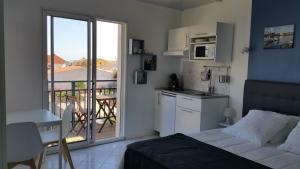 a bedroom with a bed and a kitchen with a balcony at La Chaumette in Les Sables-dʼOlonne
