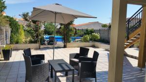 a patio with a table and chairs and an umbrella at La Chaumette in Les Sables-dʼOlonne