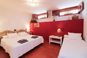 グアダルーペにあるCasa rural Llana 12の赤い壁のベッドルーム1室(ベッド2台付)