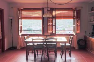 comedor con mesa, sillas y ventanas en Casa rural Llana 12, en Guadalupe