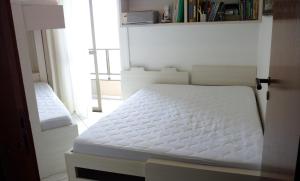 a white bed in a room with a window at Lindo Apto Itapema Meia Praia Frente ao Mar, 6 pessoas, alto padrão in Itapema