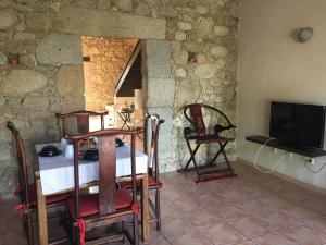 a living room with a table and a tv and a stone wall at LaEstancia in Madrigal de la Vera