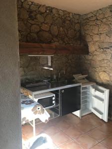 a kitchen with a stove and a sink in a stone wall at LaEstancia in Madrigal de la Vera