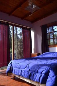 - une chambre avec un lit bleu dans une pièce dotée de fenêtres dans l'établissement Cabañas Paraiso Duplex 7 solo familias, à Mar del Plata