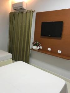 a room with a tv and a bed and a curtain at Hotel Itamarati in Uberlândia