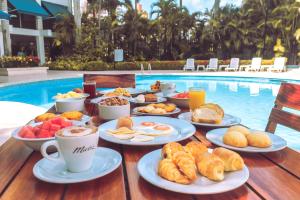 a table topped with plates of food next to a pool at Hotel Barranquilla Plaza in Barranquilla