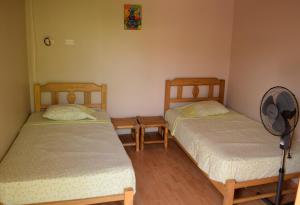two twin beds in a room with a fan at La Pachamama in Máncora