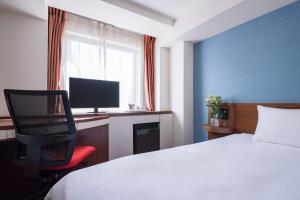 a hotel room with a television and a bed at the b hachioji in Hachioji