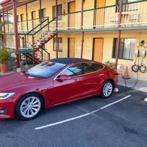 czerwony samochód zaparkowany na parkingu przed budynkiem w obiekcie Harbour Lodge Motel w mieście Gladstone