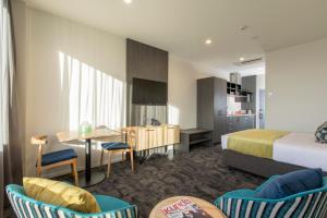 a hotel room with a bed and a table and chairs at Quest on Manchester Serviced Apartments in Christchurch