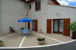 a patio with a table and an umbrella in front of a building at Chambres d'Hôtes Mazurier in Cozes