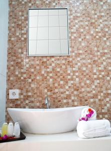 Una bañera blanca en un baño con una pared de ladrillo. en Seno Guesthouse & Cafe, en Uluwatu 49 fotos más