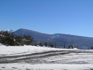 una carretera cubierta de nieve con una valla y montañas en Carpe diem en San Martín de los Andes