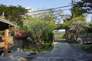 an entrance to a house with trees and pink flowers at Pondok Bali Sea View Bungalow in Lovina