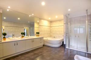 La salle de bains est pourvue de 2 lavabos, d'une baignoire et de toilettes. dans l'établissement Lake Hayes Luxury Residence, à Queenstown